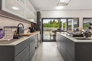 Cocina moderna con una isla central, comedor con mesa y sillas, y vista a un patio exterior a través de puertas de vidrio.