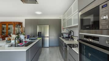 A modern kitchen with stainless steel appliances, a built-in oven, and a large island with a sink.