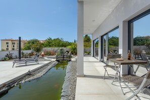 A modern outdoor patio with a pool, lounge chairs, and a dining area with a table and chairs. - Studio 'Mariana' with Atlantic View, Culinary Experience and Unique Hospitality (Gaula)