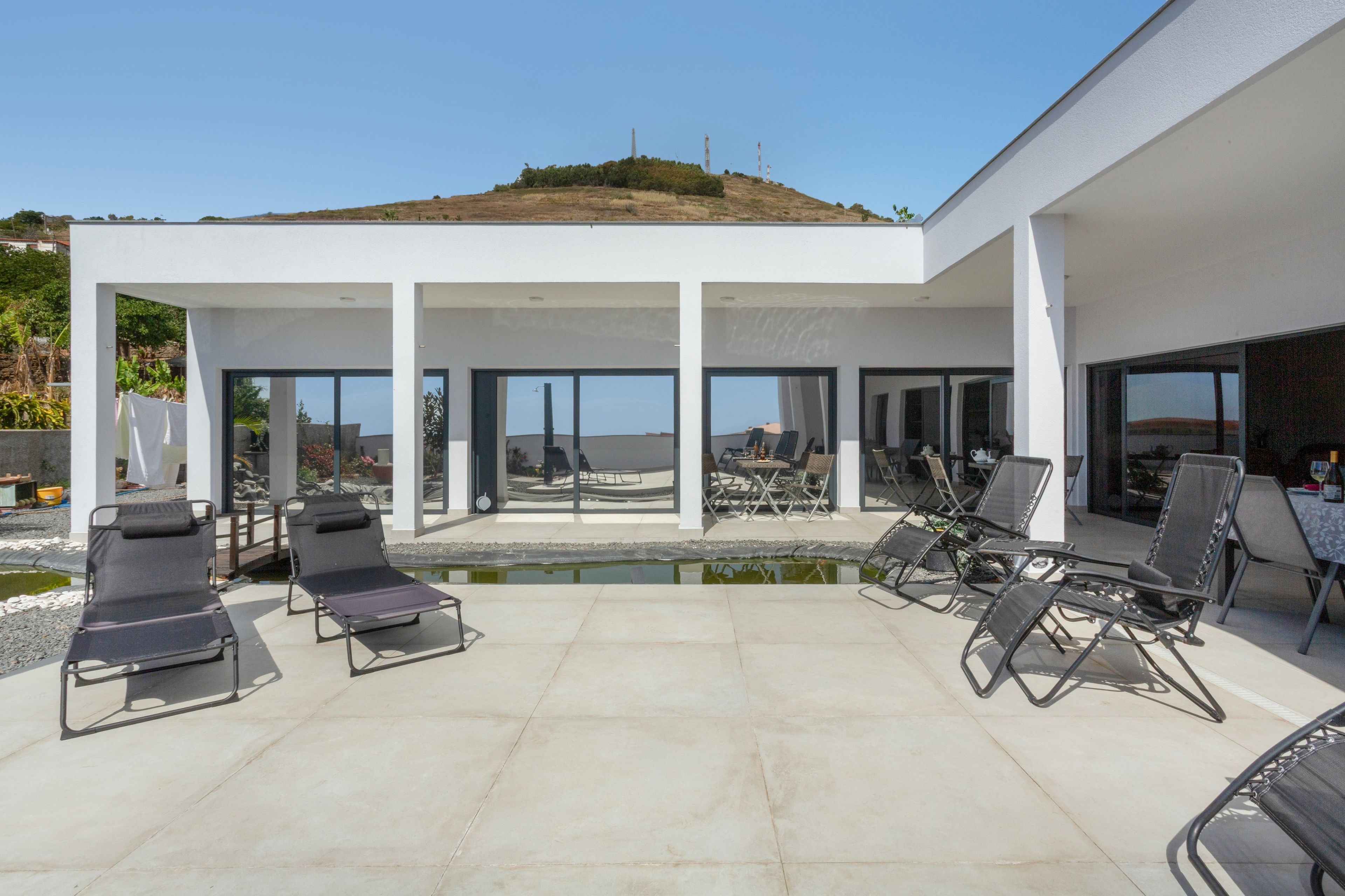 A modern outdoor patio with lounge chairs, a small pool, and a view of the landscape.