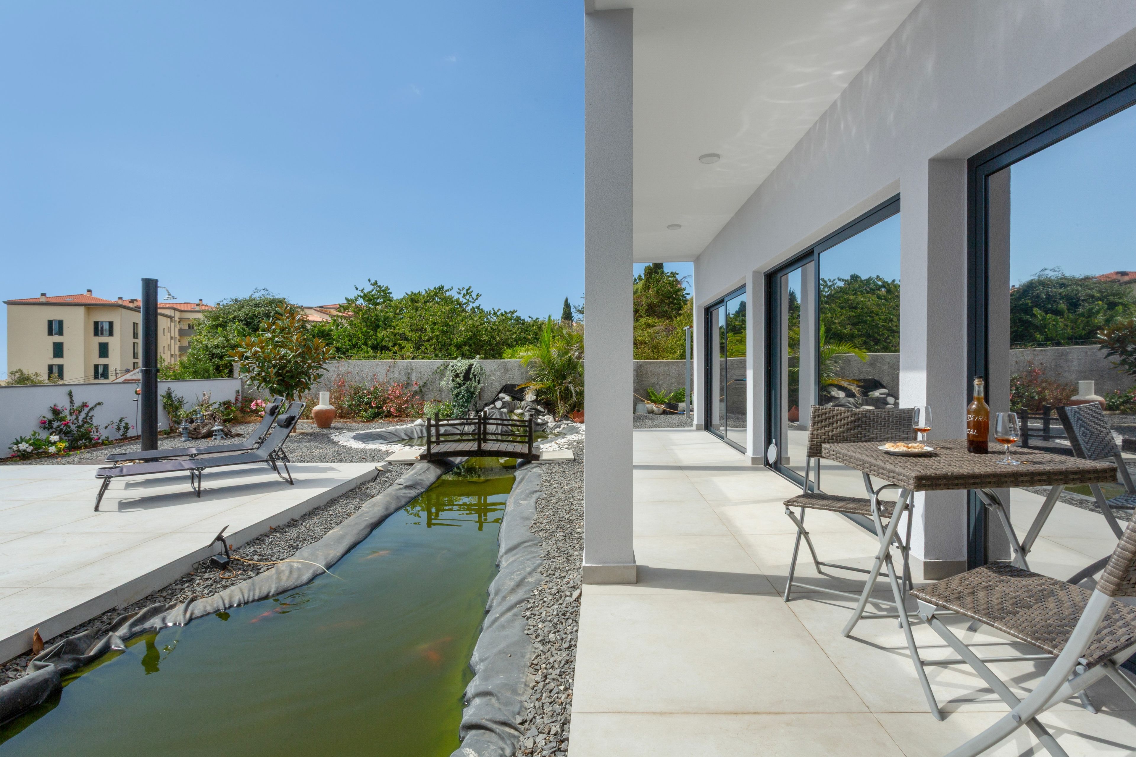 Eine moderne Außenpatio mit Pool, Liegestühlen und einem Essbereich mit Tisch und Stühlen.