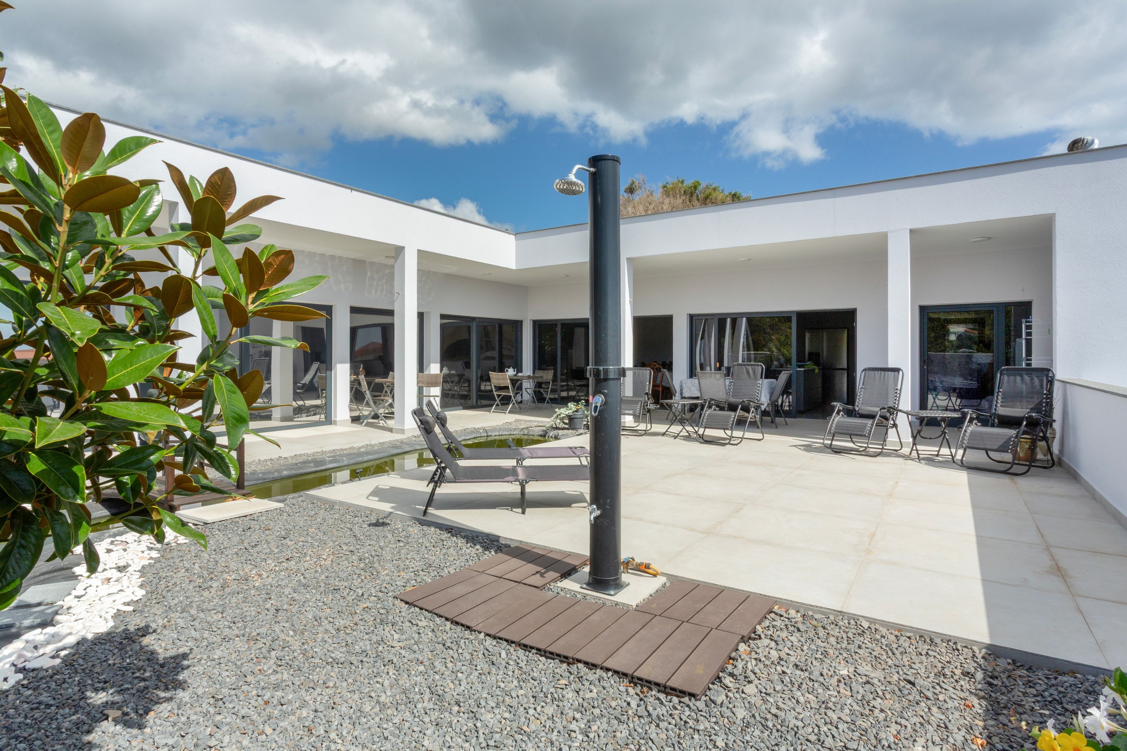 A modern outdoor seating area with a pool, surrounded by a white building with large windows.
