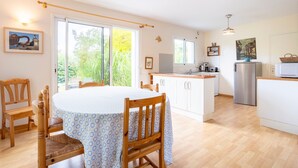 A modern kitchen with white cabinets, a stainless steel refrigerator, and a dining area with a round table and wooden chairs.