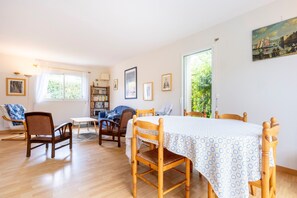 Un coin repas avec une table recouverte d’une nappe à motifs, entourée de chaises en bois.