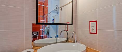 A bathroom with two sinks, a mirror, and a red-framed electrical outlet.