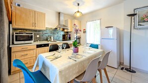 Una cocina compacta con comedor, armarios de madera, microondas, estufa y refrigerador.