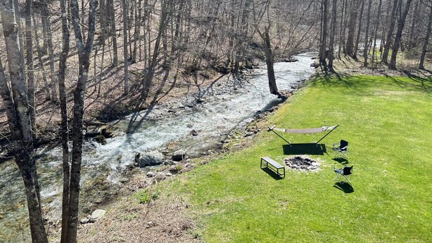A grassy area with a bench and chairs near a stream, surrounded by trees. - Enjoy the views and Vermont Vibes (Sandgate)