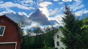 A red barn and a white house with a grassy yard and trees in the background. - Enjoy the views and Vermont Vibes (Sandgate)