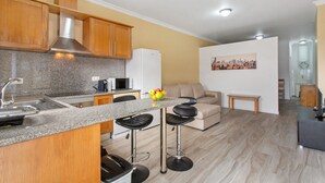 A modern kitchen with granite countertops, stainless steel appliances, and a dining area with bar stools. - Apartment 'Casa Viva' with Sea View, Shared Terrace and Wi-Fi (Machico)