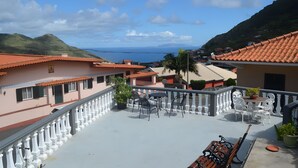 A balcony with outdoor furniture, a railing, and a view of the sea and hills. - Apartment 'Casa Viva' with Sea View, Shared Terrace and Wi-Fi (Machico)