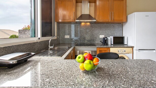 A kitchen with granite countertops, wooden cabinets, a stainless steel range hood, a microwave, and a Samsung refrigerator. - Apartment 'Casa Viva' with Sea View, Shared Terrace and Wi-Fi (Machico)