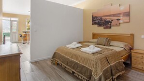 A bedroom with a bed, a nightstand, a wooden dresser, and a view of the outside. - Apartment 'Casa Viva' with Sea View, Shared Terrace and Wi-Fi (Machico)