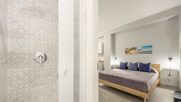 Un dormitorio con cama, almohadas, un cuadro y una mesita de noche.