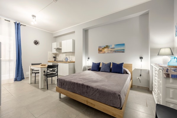 Une chambre à coucher avec un lit, un bureau, une chaise, une horloge et un tableau accroché au mur.