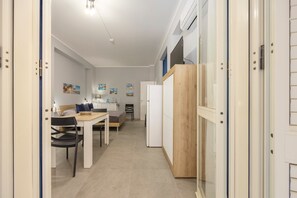 Un couloir étroit comprenant un coin repas, un lit et une armoire en bois.
