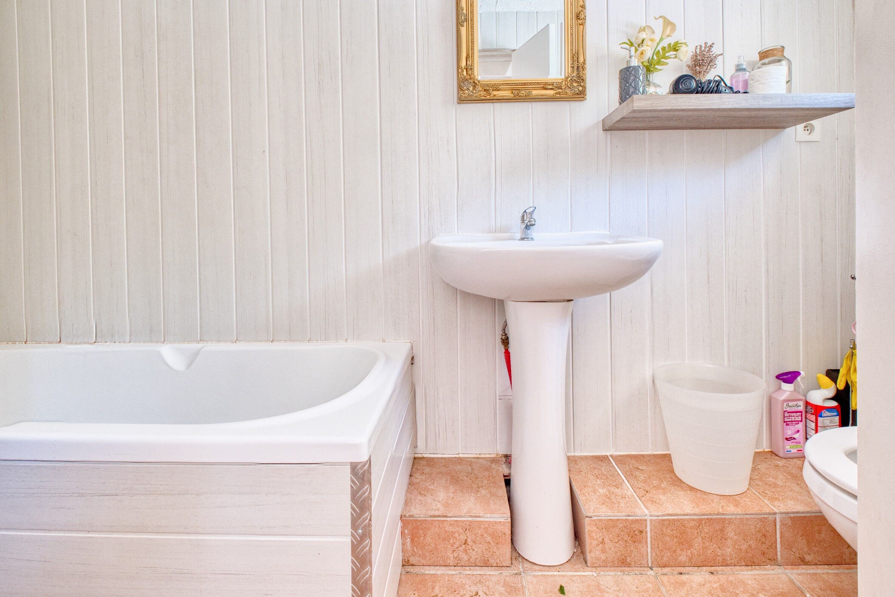 A bathroom with a bathtub, a pedestal sink, and a toilet.