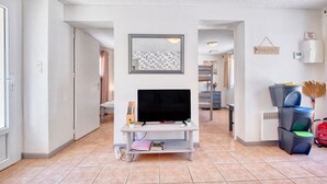 Un salón con un televisor de pantalla plana sobre un soporte blanco, un espejo montado en la pared y un cartel que dice 'WELCOME'.