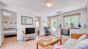 Un espacio habitable compacto con kitchenette, televisor, cama y zona de comedor.