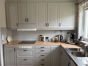 A kitchen with white cabinets, a Bosch dishwasher, a coffee maker, and a kettle. - Holiday home in Ellös, 300 m to a sandy beach | SE09113 (Ellös)