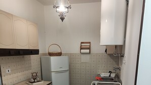 A compact kitchen with white cabinets, a refrigerator, a sink, and a stove. - The House in the Green (Lortallo)