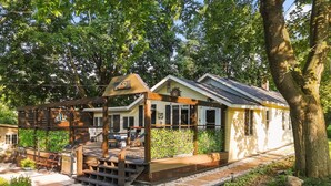 Ein Haus mit überdachter Veranda, einer kleinen Terrasse und einem Garten.