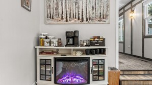 Ein Kamin mit modernem Design, darüber eine Kaffeestation und ein Gemälde an der Wand.