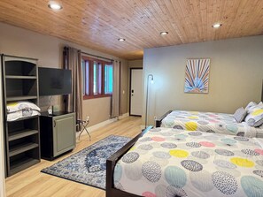 Ein Zimmer mit zwei Betten, einem Fernseher, einem Schreibtisch und einem Kleiderschrank.