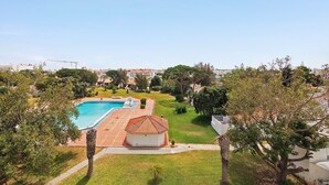Una piscina, un edificio pequeño y follaje circundante.