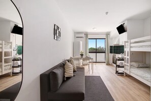 Ein modernes Zimmer mit einer Couch, Etagenbetten, einem Esstisch und Blick ins Freie.