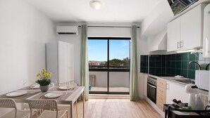Una cocina moderna con comedor, vista a través de un ventanal y un balcón pequeño.