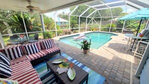 A covered outdoor area with a pool, seating, and a view of the surrounding greenery.