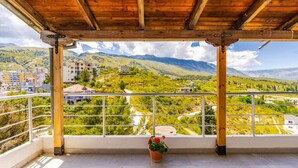 A covered balcony with a view of a mountainous landscape and buildings. - Hillside Apartment Gjirokaster by PikHost (Gjirokastër)