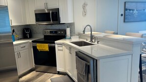 A modern kitchen with white cabinetry, stainless steel appliances, and a wooden floor. - Beachfront 2BR/2BA Condo on Hutchinson Island w/ Private Garage (Fort Pierce)