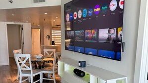 A modern living room with a flat-screen TV mounted on the wall displaying various streaming services. - Beachfront 2BR/2BA Condo on Hutchinson Island w/ Private Garage (Fort Pierce)