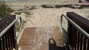 A wooden boardwalk leading to a sandy beach with waves in the background. - Beachfront 2BR/2BA Condo on Hutchinson Island w/ Private Garage (Fort Pierce)