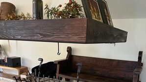 A fireplace with a brick surround, a wooden bench, and a hanging shelf above. - Villa Gioia on the Euganean Hills (Torreglia)