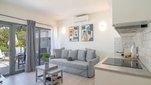 Una sala de estar moderna con un sofá gris, una mesita y una cocina con lavaplatos y encimera.