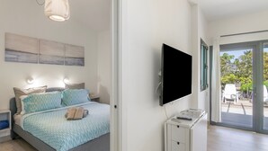 Un dormitorio moderno con cama, televisor de pantalla plana y vista a través de un ventanal.