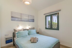 Una camera da letto con un letto, un comodino, un'opera d'arte appesa al muro, una finestra e un lampadario.