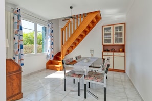Un comedor con mesa, sillas, una escalera y un armario.