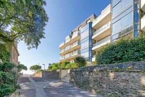 Un immeuble résidentiel à plusieurs étages, doté de balcons, d’un mur en pierre et d’un chemin pavé.