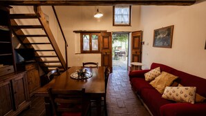 A dining area with a wooden table and chairs, a red sofa, a staircase, and a painting on the wall.