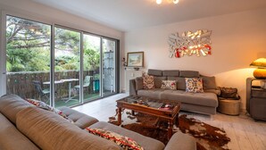 Un salon moderne avec un canapé, une table basse et une grande fenêtre donnant sur un jardin.