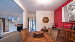Un coin repas avec une table en bois, des chaises en osier et un mur d’accent de couleur rouge.