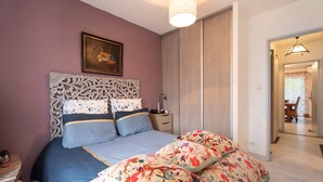 Une chambre à coucher avec un lit, une table de chevet, une lampe et une porte donnant sur une autre pièce.