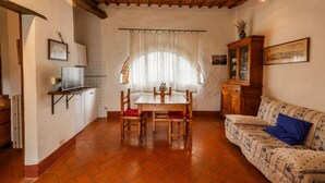 A cozy room with a wooden ceiling, a dining table with chairs, a sofa, a cabinet, and a television on a stand.