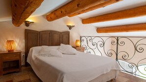 Une chambre à coucher avec un grand lit, une tête de lit en bois, deux lampes de chevet et une vue à travers une rambarde en métal.