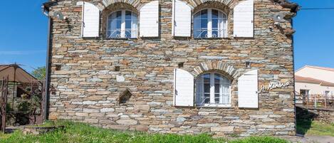 Un bâtiment en pierre doté de trois fenêtres en arc de cercle et d’une enseigne indiquant « Hôtel de la Mare ».