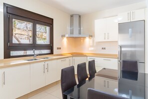 A modern kitchen with a stainless steel refrigerator, a built-in oven, and a window with a view of the outdoors.