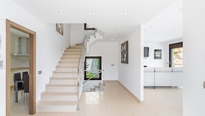 Un interior moderno con una escalera, una zona de cocina y un comedor.